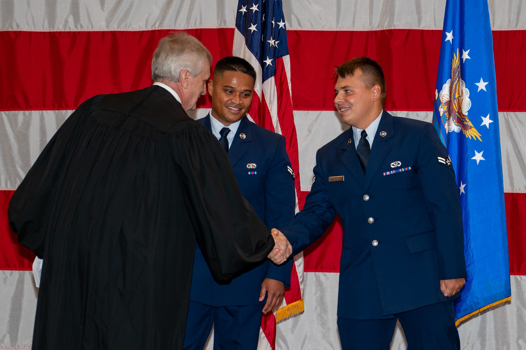 Honorable Judge Mark Hornsby, shakes the hands of U.S. Air Force Airman 1st Class Atson Nameta, 2nd Logistics Readiness Squadron individual protection equipment apprentice, and Airman 1st Class Tykhon Rudenok, 2nd Civil Engineer Squadron heating, ventilation and air conditioning apprentice, after administering the Oath of Allegiance during a Naturalization Ceremony at Barksdale Air Force Base, Louisiana, July 15, 2025. Hornsby, who administered the Oath of Allegiance, is the U.S. Magistrate for the Western District of Louisiana. (U.S. Air Force photo by Airman 1st Class Jaiyah Lewis)