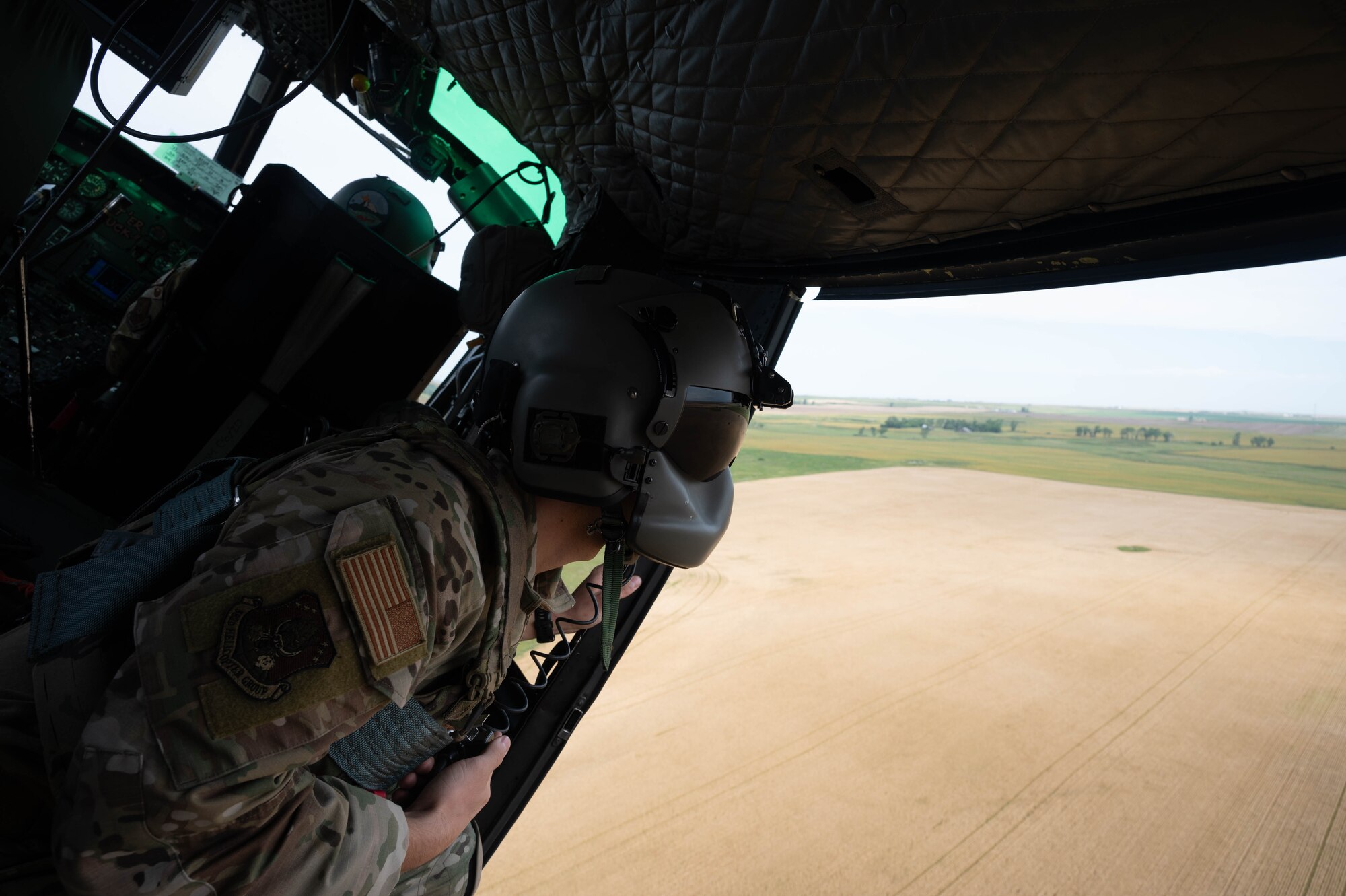 U.S. Air Force Staff Sgt. Garrett Hightower, a 54th Helicopter Squadron special missions aviator, looks out of a UH-1N Iroquois helicopter during a turn at Minot Air Force Base, North Dakota, Aug. 21, 2025. The UH-1N has been stationed at Minot AFB since March 20, 1980 and is scheduled to remain until 2029, with the MH-139A expected to arrive in 2027. (U.S. Air Force photo by Airman 1st Class Wesley Davies)