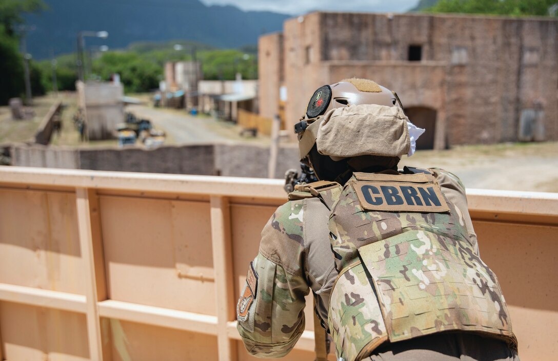 A U.S. service member in camo and a tactical vest participates in an exercise to prepare and train for chemical, biological, radiological, and nuclear warfare,