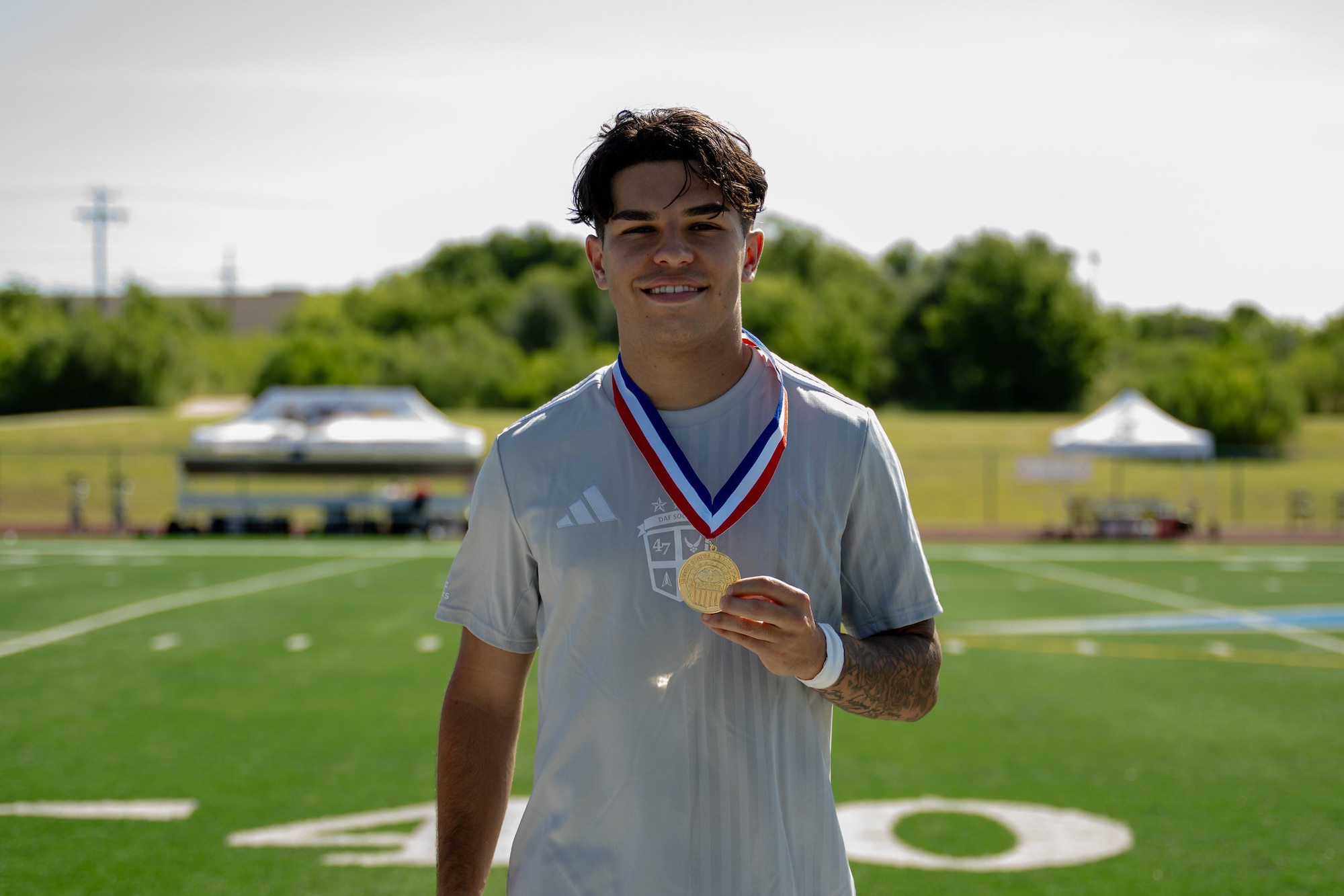 A man stands on a field with a medal