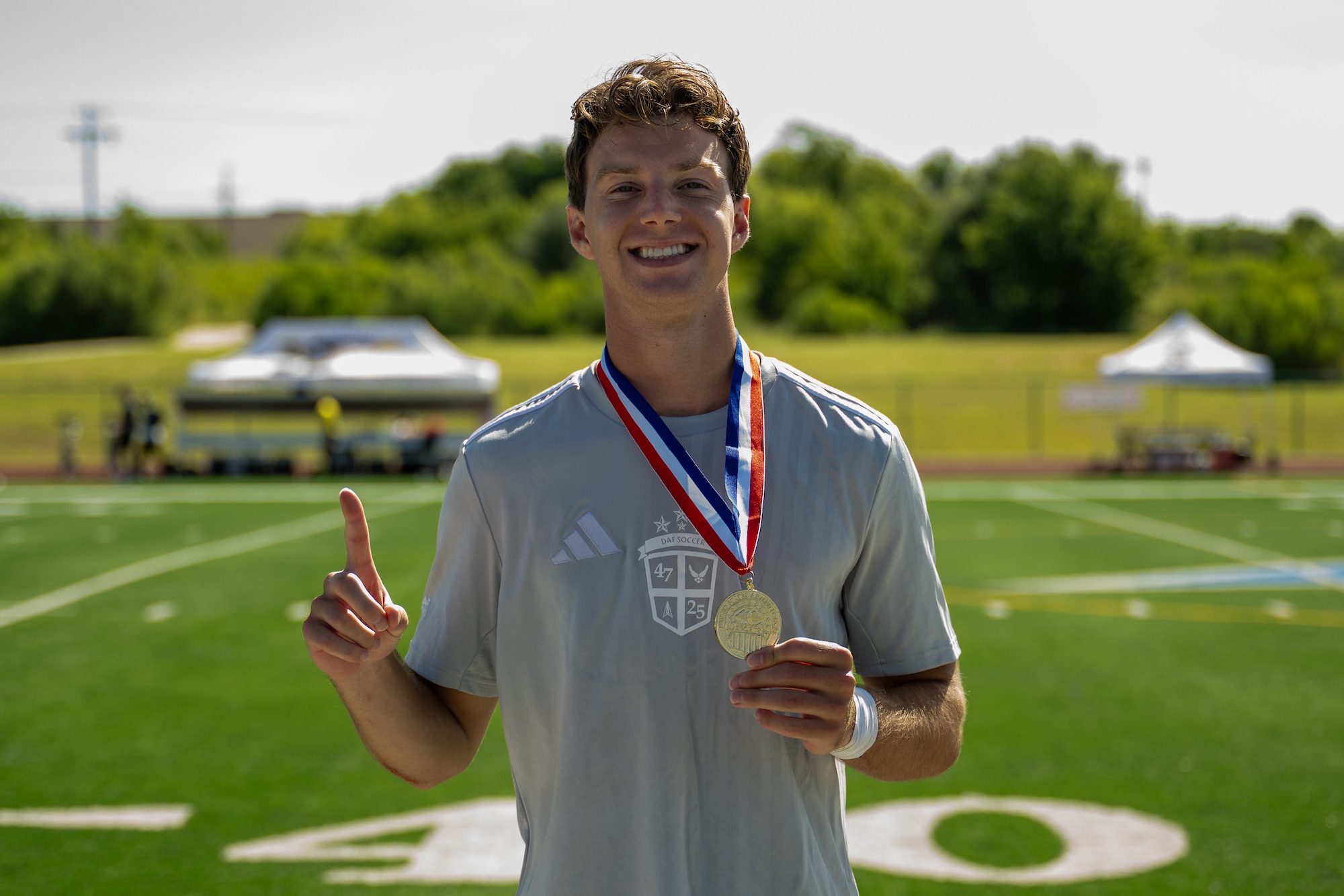 A man stands on a field with a medal