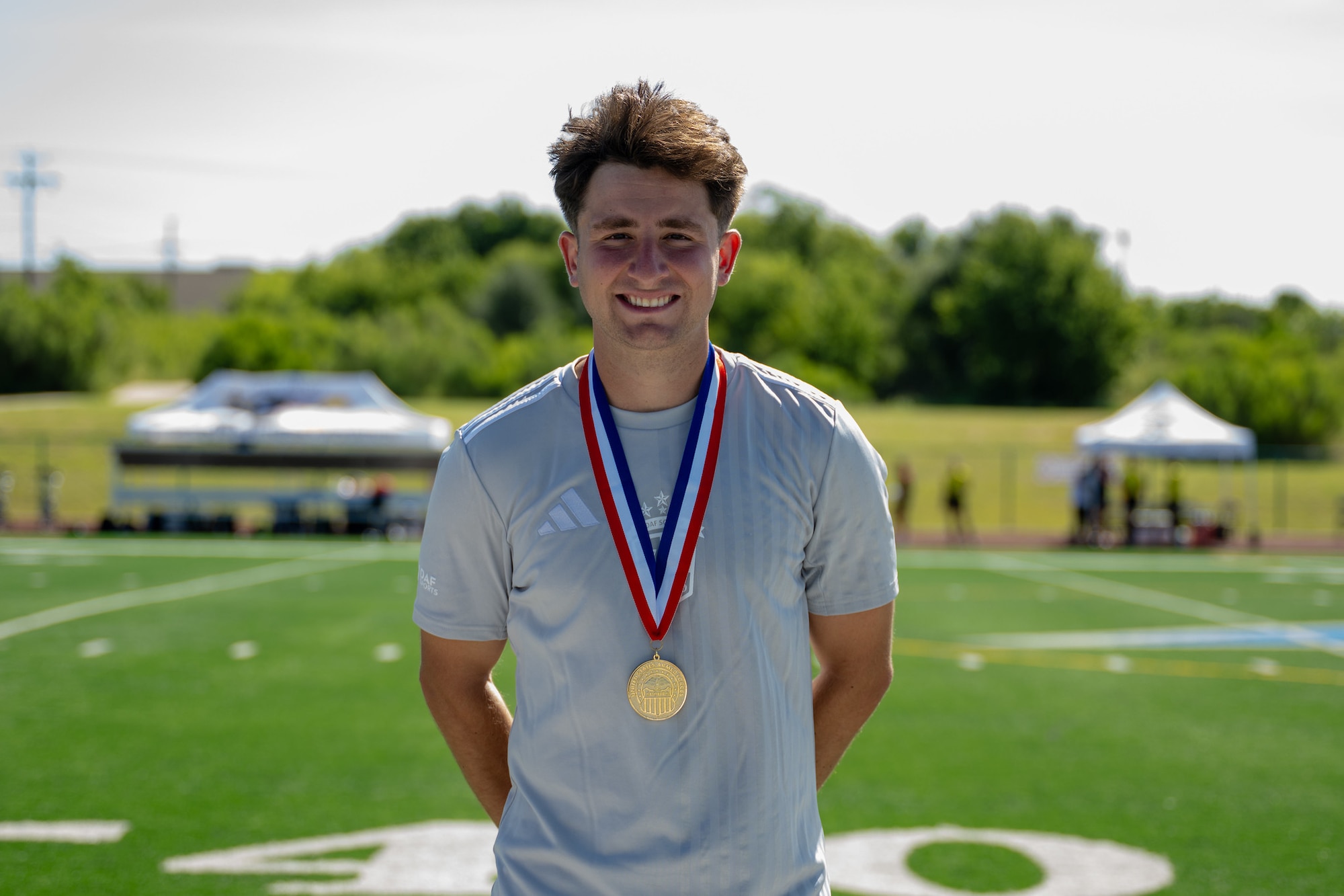 A man stands on a field with a medal