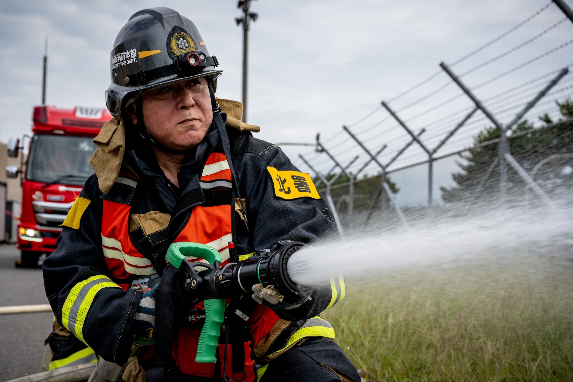 A firefighter assigned to the Tsugaru City Fire Department uses a fire hose to extinguish a simulated fire during a medical evacuation training scenario at Shariki Communications Site, Japan, Aug. 19, 2025.