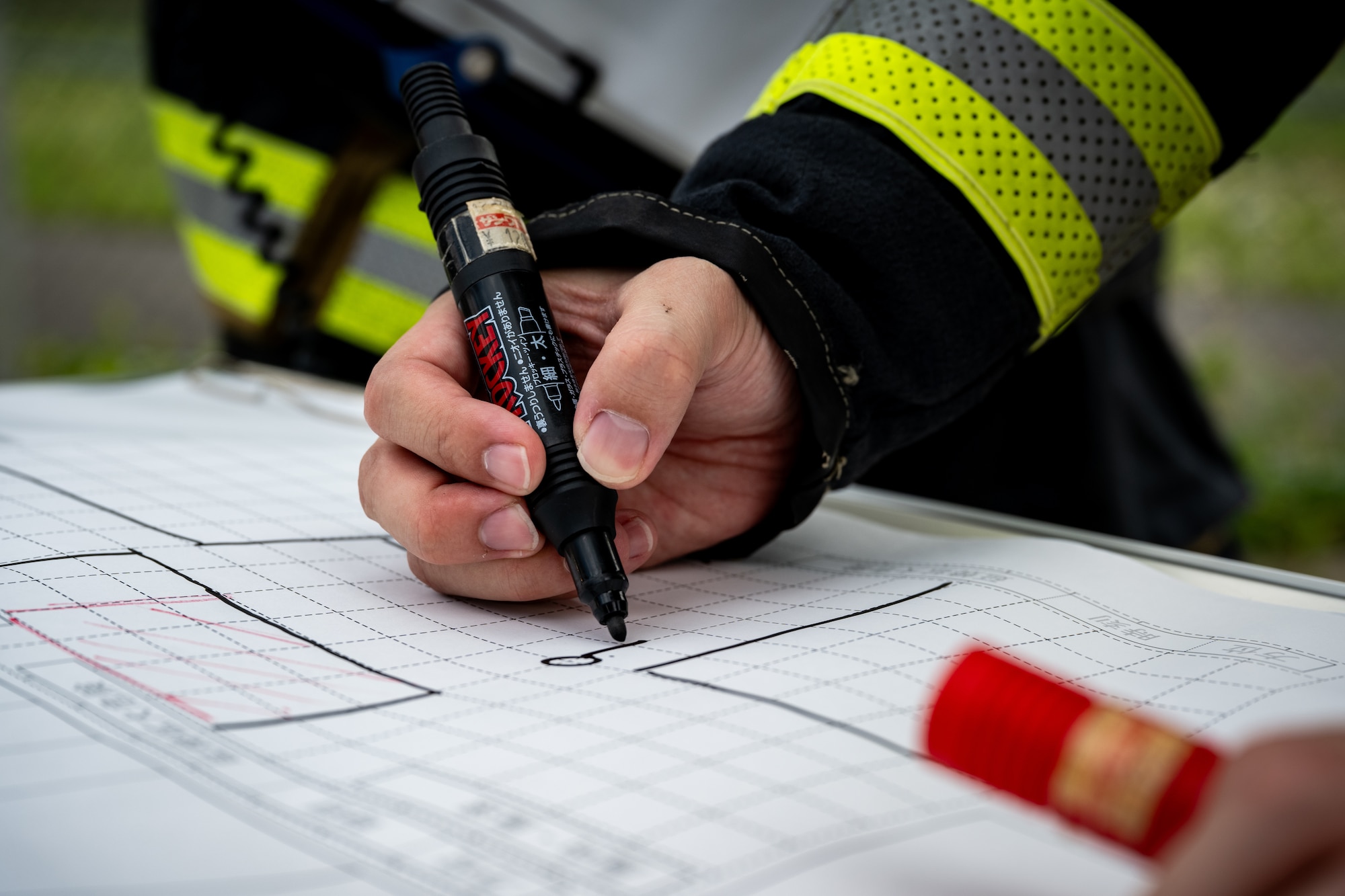A firefighter assigned to the Tsugaru City Fire Department creates a map of the incident during a medical evacuation training scenario at Shariki Communications Site, Japan, Aug. 19, 2025.