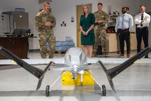 U.S. Air Force 1st Lt. Josh Sheldon, left, Task Force 99 electrical engineer, presents a drone model to U.S. Sen. Joni Ernst within the U.S. Central Command area of responsibility, Aug. 21, 2025. Ernst visited with members of TF99 to see their adaptation of commercial unmanned aerial systems. (U.S. Air Force photo by Staff Sgt. Sean Moriarty)