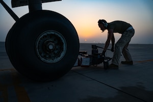 U.S. Air Force Staff Sgt. Davin Lawrence, 156th Expeditionary Airlift Squadron crew chief, lifts a nose tire on a C-17 Globemaster III within the U.S. Central Command area of responsibility, Aug. 11, 2025. Crew chiefs are tasked with conducting preflight and postflight procedures to prepare aircraft for missions, and ensure proper recovery after landing. (U.S. Air Force photo by Senior Airman Amanda Jett)