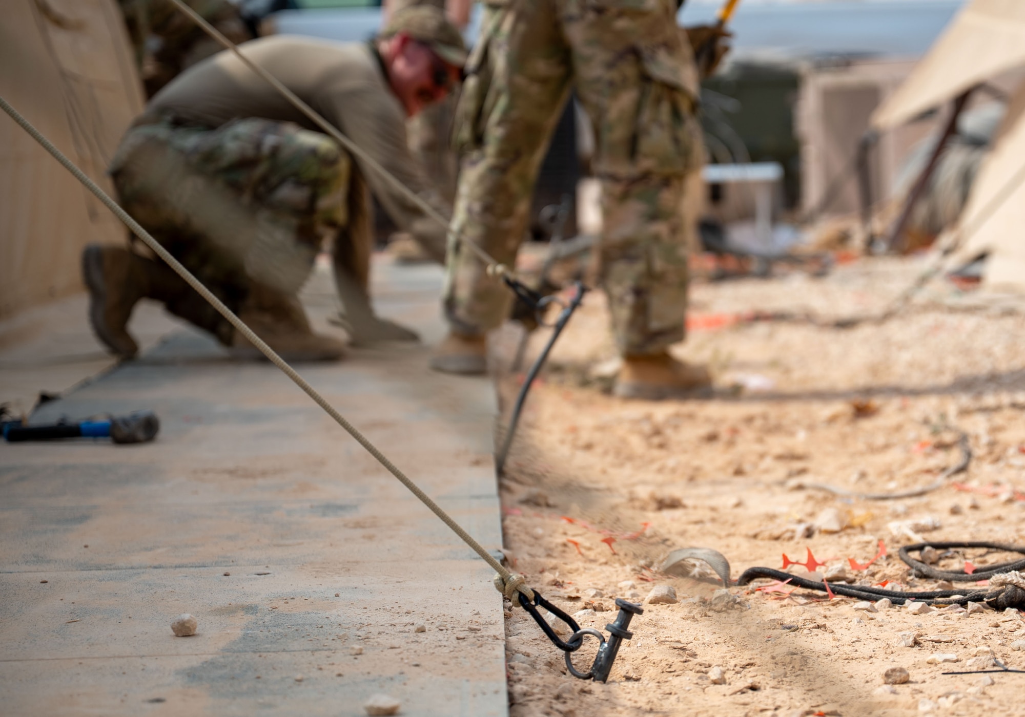 U.S. Airmen assigned to the 378th Expeditionary Civil Engineer Squadron secure tie down stakes for a Small Shelter System.