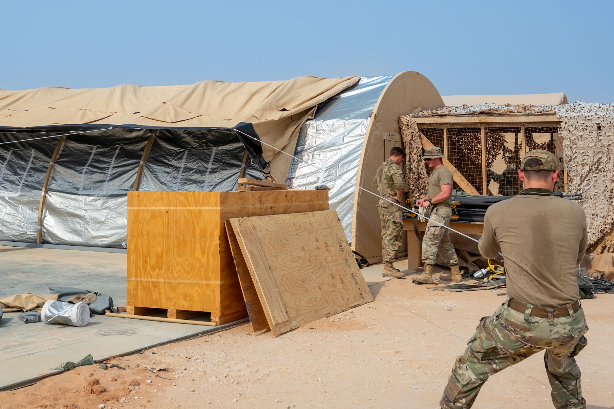 U.S. Air Force Tech. Sgt. Drew Davis, 378th Expeditionary Civil Engineer Squadron structures noncommissioned officer in charge, uses a pull rope to put the main cover on a Small Shelter System.