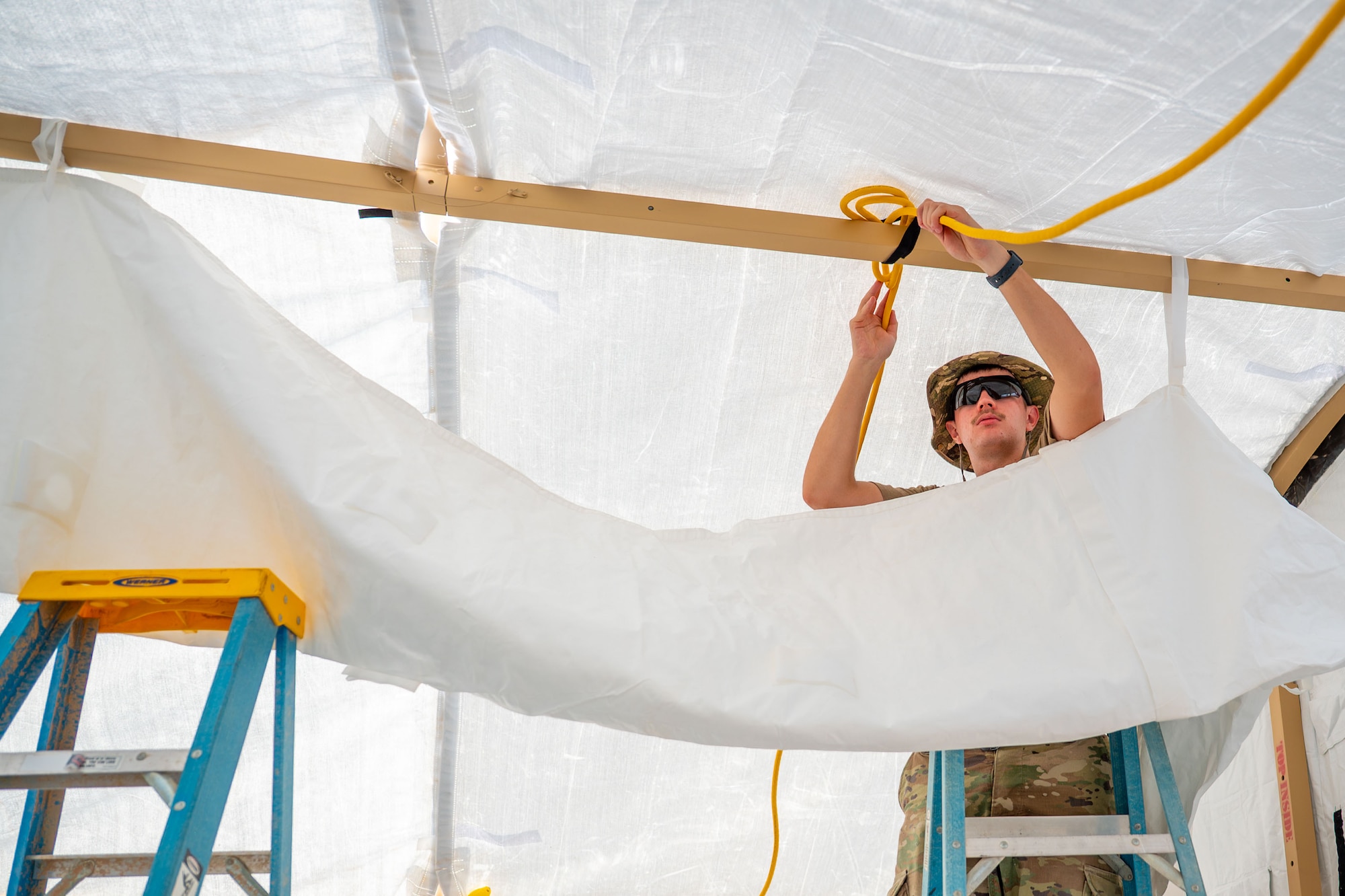 U.S. Air Force Airman 1st Class Nolan Pryor, 378th Expeditionary Civil Engineer Squadron structural journeyman, rigs a power cord for lighting and equipment.