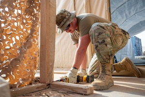 U.S. Air Force Airman 1st Class Nathaniel Cooper, 378th Expeditionary Civil Engineer Squadron structural journeyman, saws a porch frame within the U.S. Central Command area of responsibility, Aug. 18, 2025.