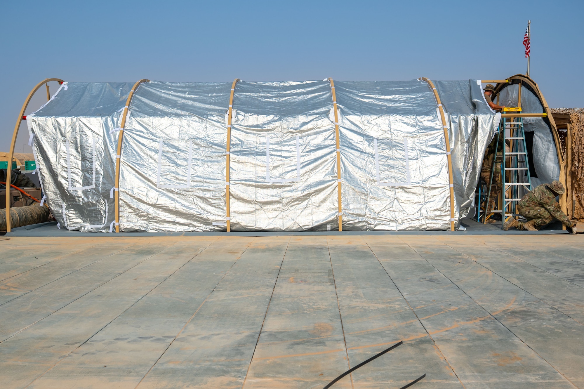 Two Airmen work on a tent.