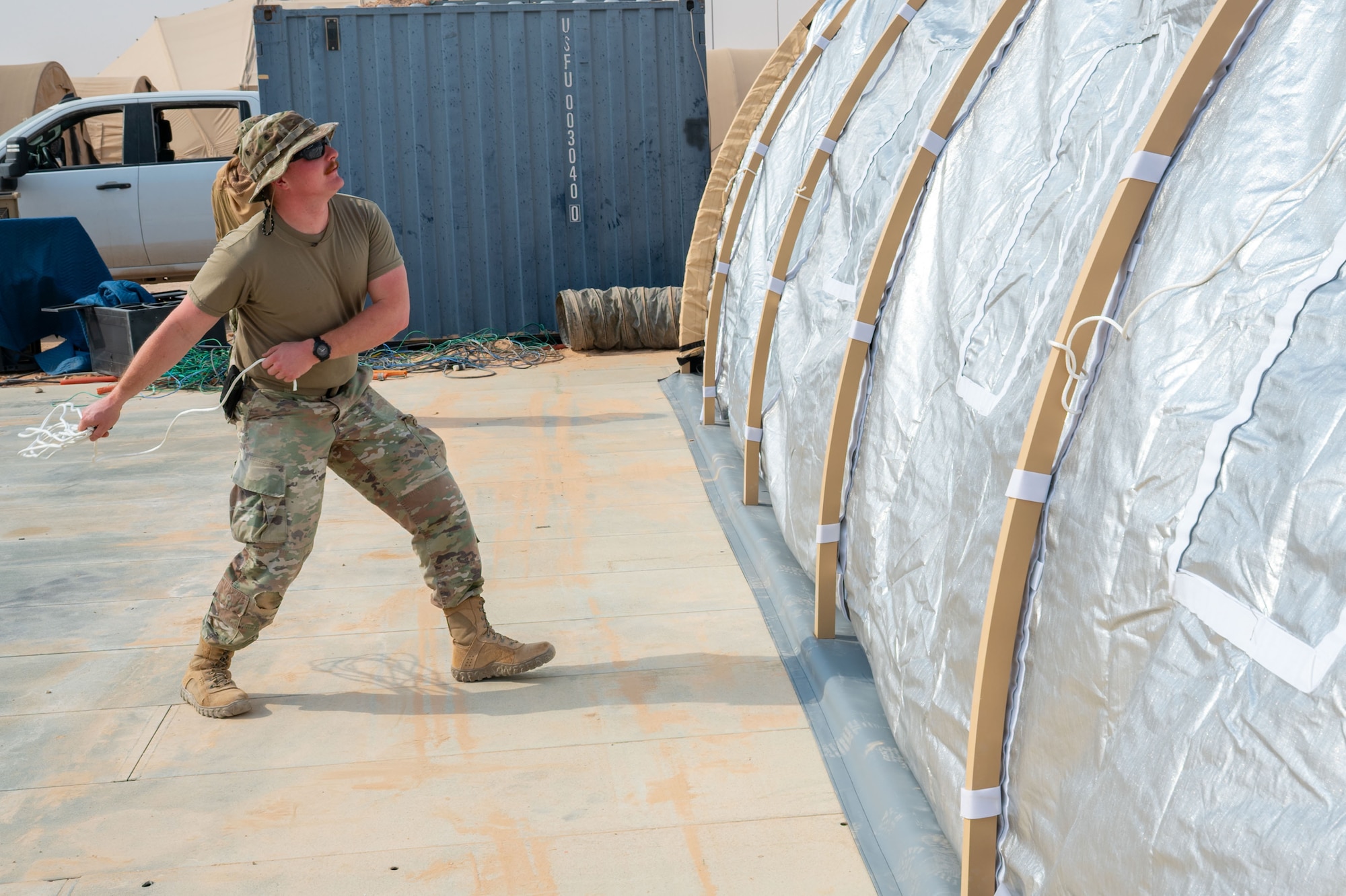 U.S. Air Force Airman 1st Class Nathaniel Cooper, 378th Expeditionary Civil Engineer Squadron structural journeyman, throws a pull rope over a Small Shelter System.