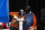 Dr. Kelly Geurts, ship sponsor of the future Columbia-class ballistic missile submarine USS Wisconsin (SSBN 827), welds her initials into the ship’s keel during its keel-laying ceremony under the supervision of General Dynamics Electric Boat welder Robert Ray Jr.