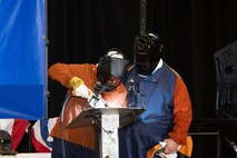 Dr. Kelly Geurts, ship sponsor of the future Columbia-class ballistic missile submarine USS Wisconsin (SSBN 827), welds her initials into the ship’s keel during its keel-laying ceremony under the supervision of General Dynamics Electric Boat welder Robert Ray Jr.