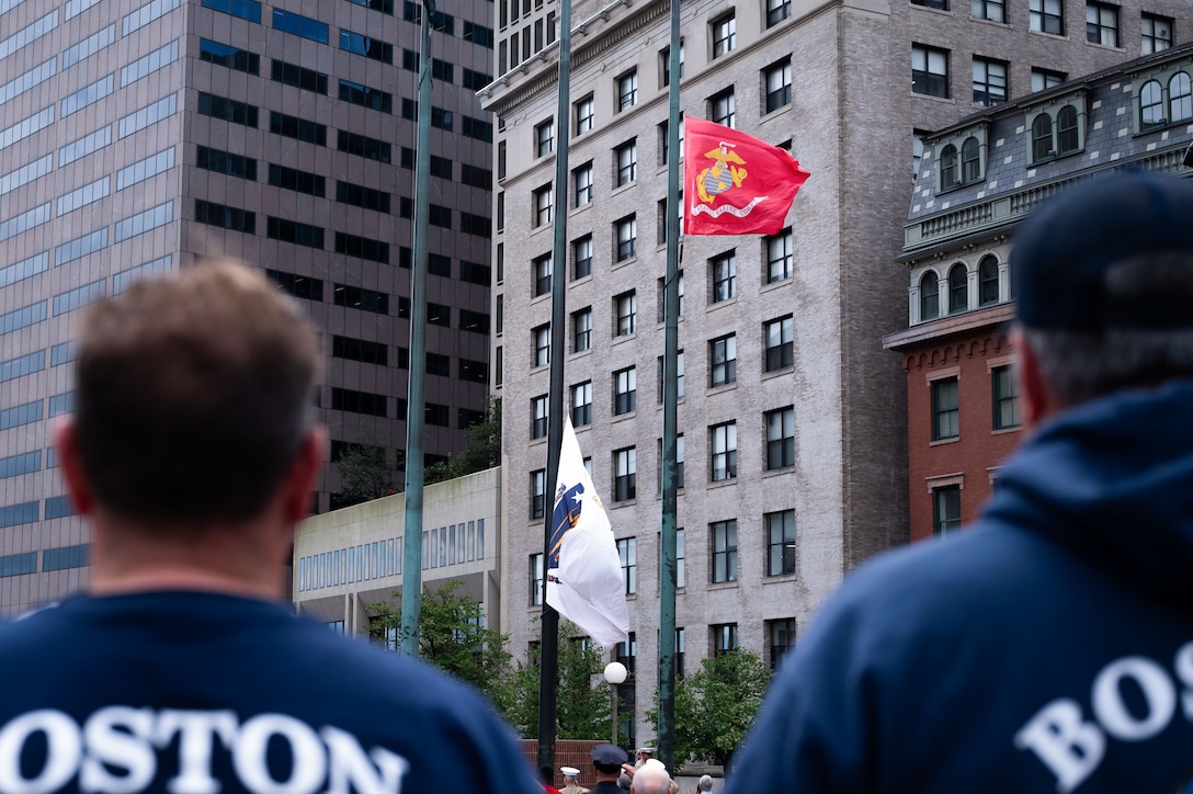 Boston fire fighters stand and watch as flags are raised during the opening ceremony hosted by U.S. Marines with the Special Purpose Marine Air-Ground Task Force-250 at the City Hall Plaza during Marine Week Boston, Aug. 21, 2025. As the Marine Corps marks its 250th year, Marines worldwide observe this historic milestone, paying tribute to generations of valor, duty, and the enduring spirit of Semper Fidelis. (U.S. Marine Corps photo by Lance Cpl. Matthew A. McDonnell)