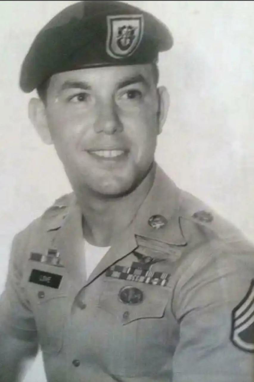 A soldier poses for a photo in black and white while wearing their uniform.