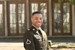 Service member smiles while posing in front of a building
