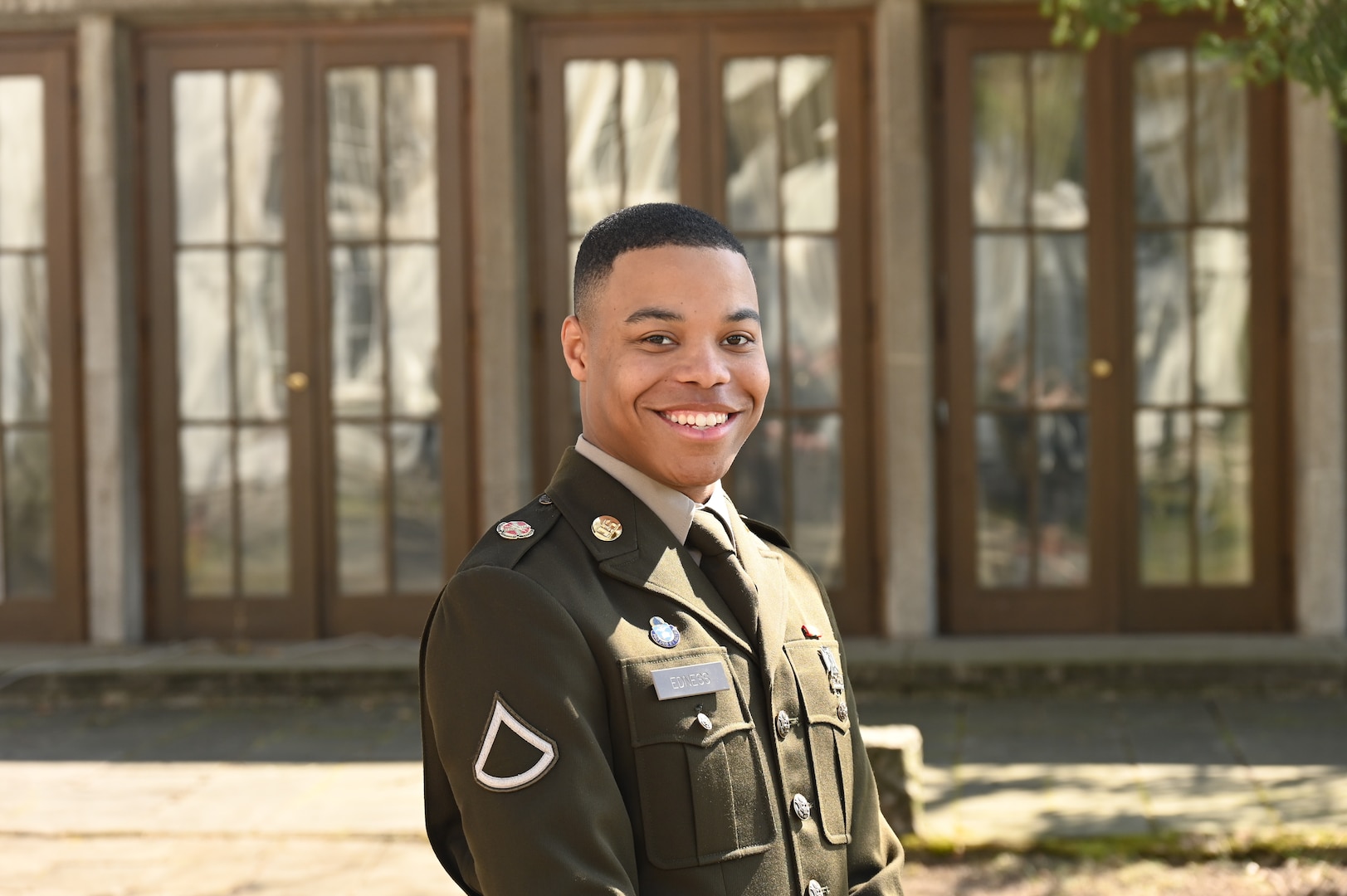 Service member smiles while posing in front of a building