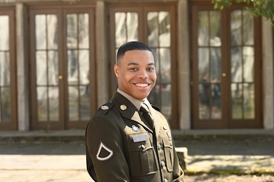 Service member smiles while posing in front of a building