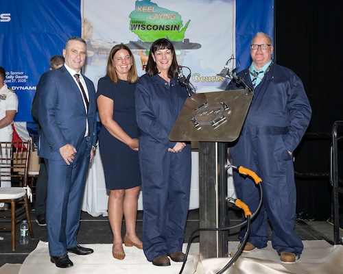 From the left, president of General Dynamics Electric Boat (GDEB) Mark Rayha, Wisconsin Matron of Honor Sarah Millar, future USS Wisconsin (SSBN 827) ship sponsor Dr. Kelly Geurts, and GDEB welder Robert Ray Jr. pose for a photo with a section of the ship’s keel featuring Dr. Geurts’ initials during the ship’s keel-laying ceremony.