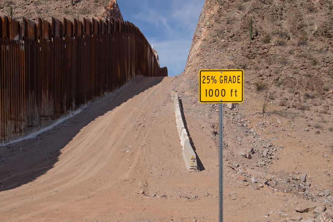 a dirt roadway next to the border fencing