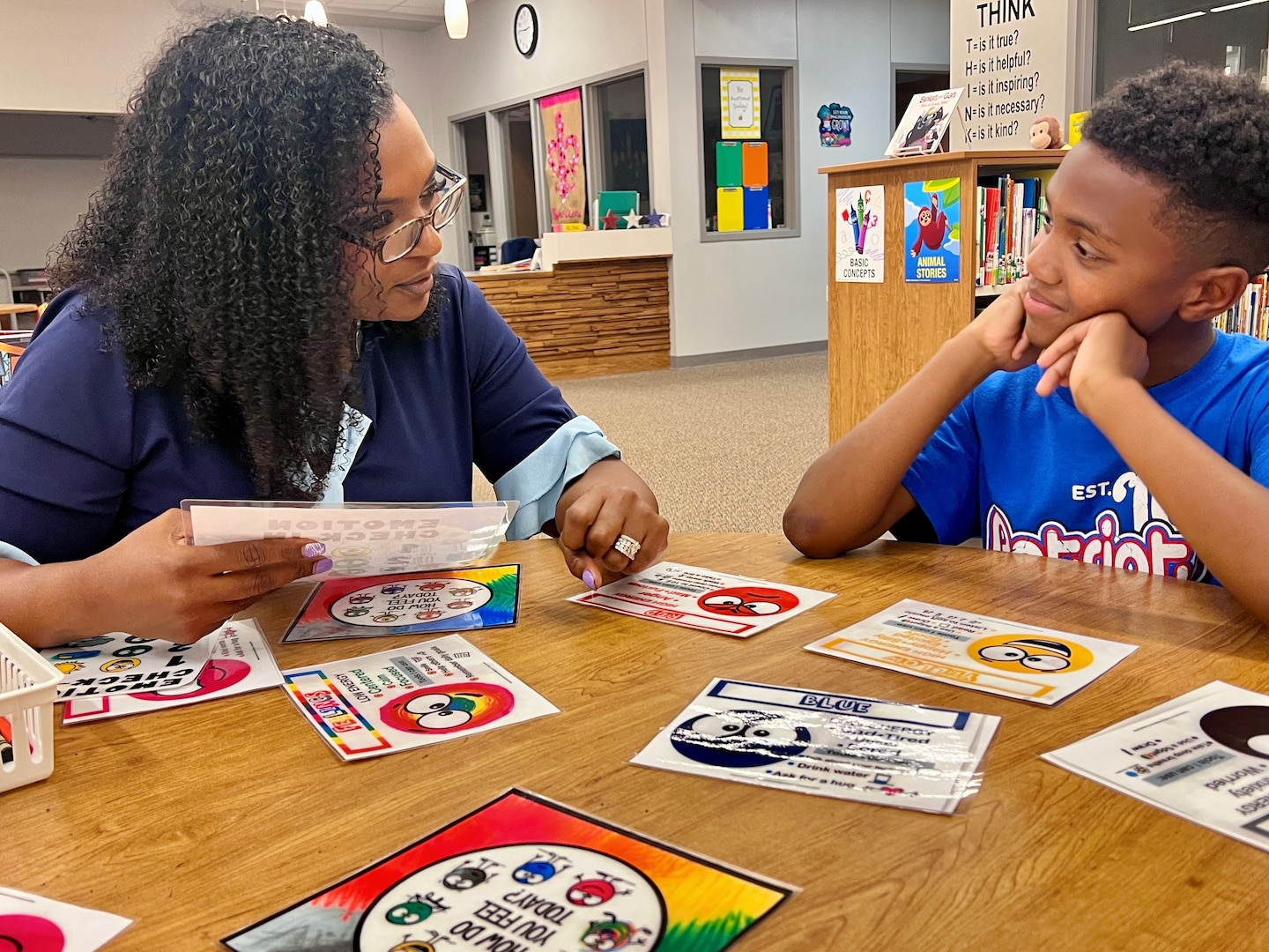Social worker working with a student in a school library setting.