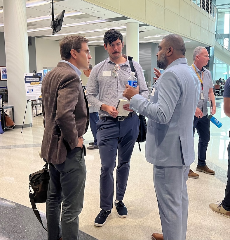 Three men standing together in discussion.