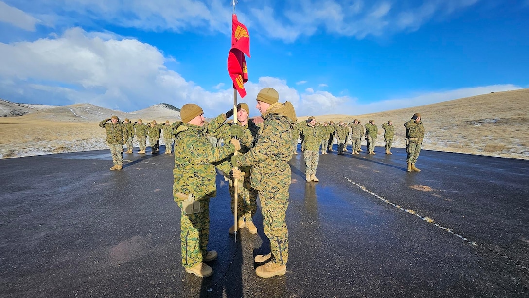 U.S. Marine Corps Capt. Avery Moore, outgoing commanding officer, 4th Law Enforcement Battalion, Force Headquarters Group, Marine Forces Reserve, passes the guidon to Capt. Garrett Gundy, incoming commanding officer, symbolizing the passing of command during a change of command ceremony at Ft. Harrison, Helena, Montana, March 20, 2025. The change of command ceremony represents the official passing of authority from the outgoing commander to the incoming commander. (U.S. Marine Corps photo by courtesy of 4th Law Enforcement Battalion)