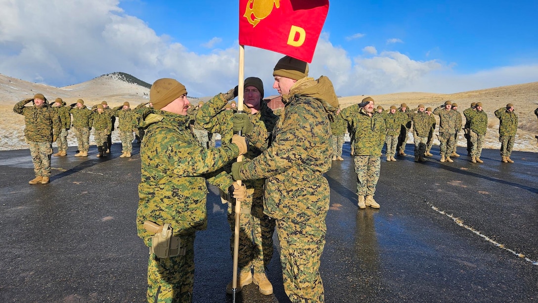 U.S. Marine Corps Capt. Avery Moore, outgoing commanding officer, 4th Law Enforcement Battalion, Force Headquarters Group, Marine Forces Reserve, passes the guidon to Capt. Garrett Gundy, incoming commanding officer, symbolizing the passing of command during a change of command ceremony at Ft. Harrison, Helena, Montana, March 20, 2025. The change of command ceremony represents the official passing of authority from the outgoing commander to the incoming commander. (U.S. Marine Corps photo by courtesy of 4th Law Enforcement Battalion)