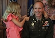 U.S. Army Col. Derek Hart's daughter, Helen and wife, Emily(top corner), pin on his new rank to his uniform during his promotion ceremony at the Louisville Country Club in Louisville, Kentucky, Aug. 20, 2025