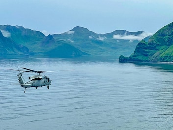 DUTCH HARBOR, Alaska (Aug. 21, 2025) — An MH-60S Sea Hawk helicopter, attached to Helicopter Sea Combat Squadron (HSC) 14, flies over Dutch Harbor during exercise Northern Edge 2025 (NE25), Aug. 21. NE25 is an exercise led by U.S. Indo-Pacific...