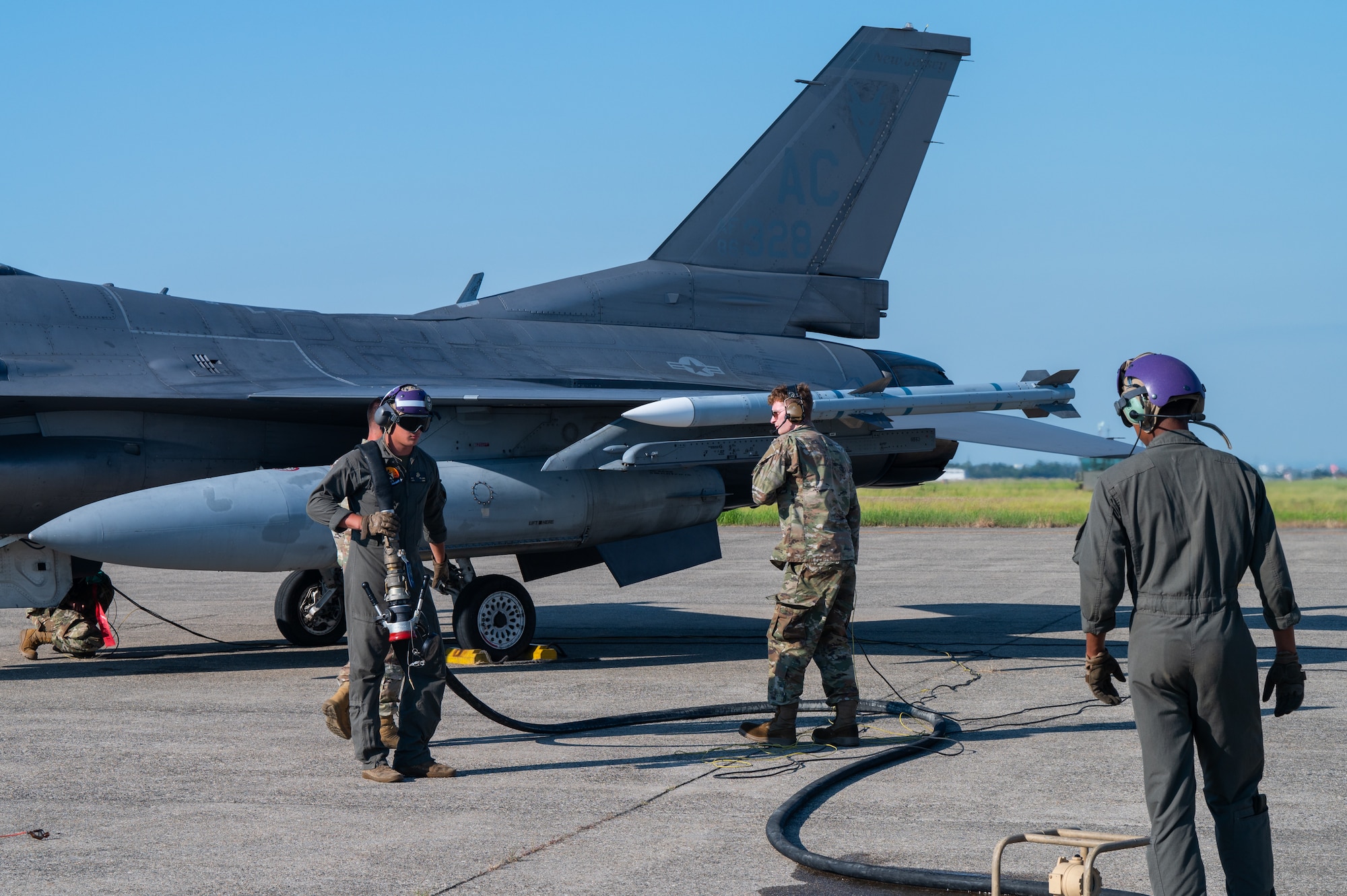 Marines assist airmen during refueling procedures on an F-16 fighter jet.
