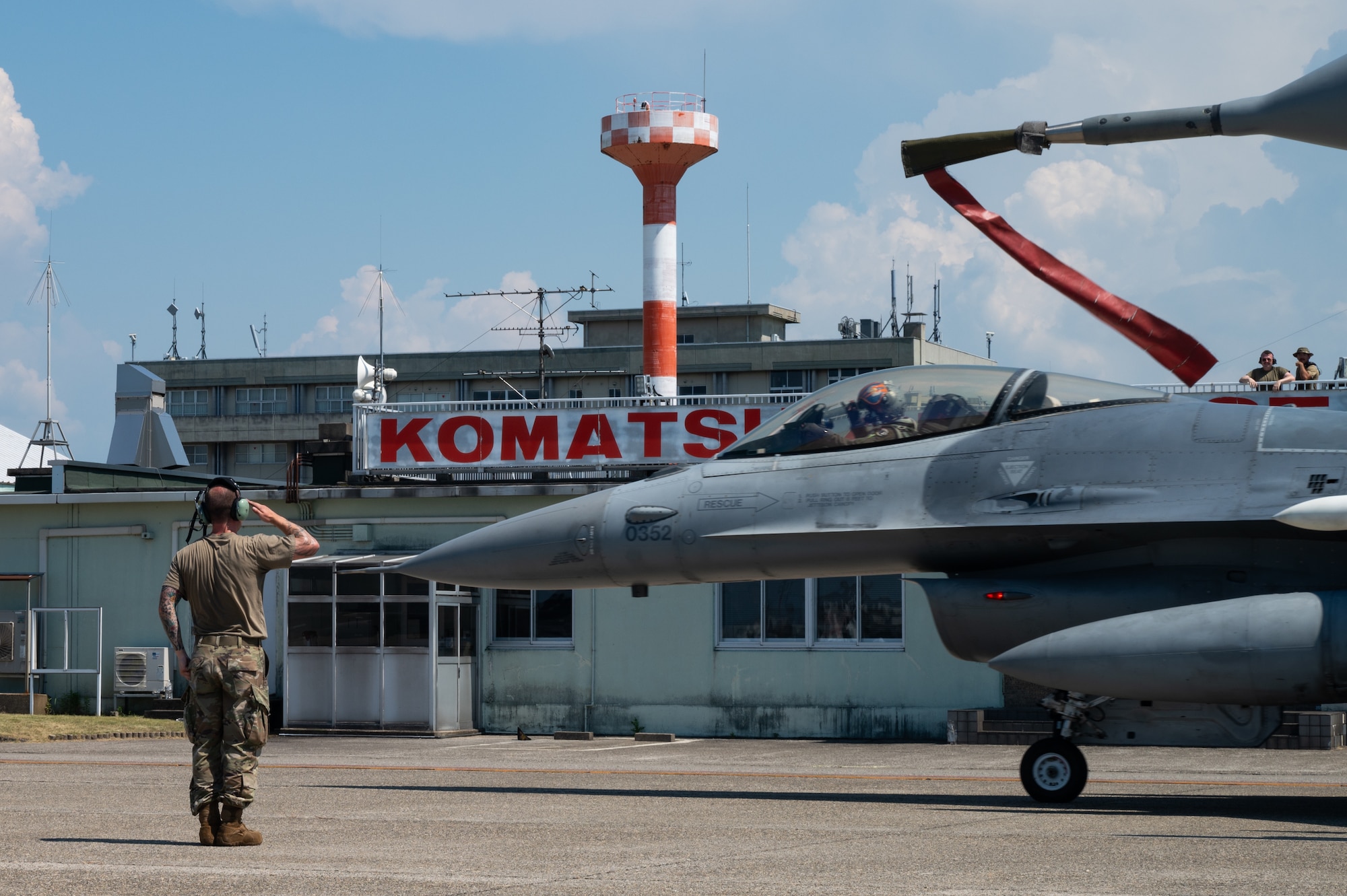 An airman salutes a pilot and an F-16 fighter jet.