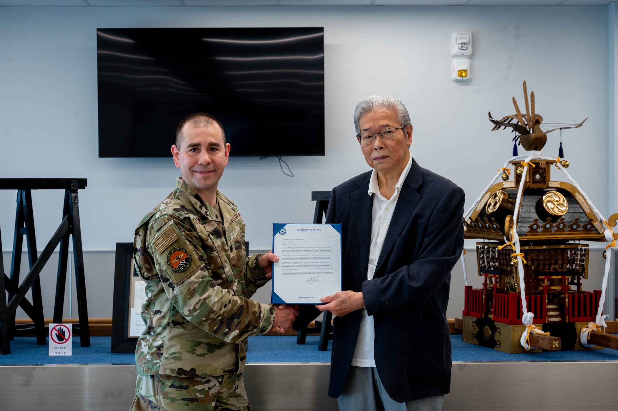 U.S. Air Force Lt. Col Shawn Cox, 730th Air Mobility Squadron commander, presents Aoki Shijegi, mikoshi shrine craftsman, with a letter of appreciation.