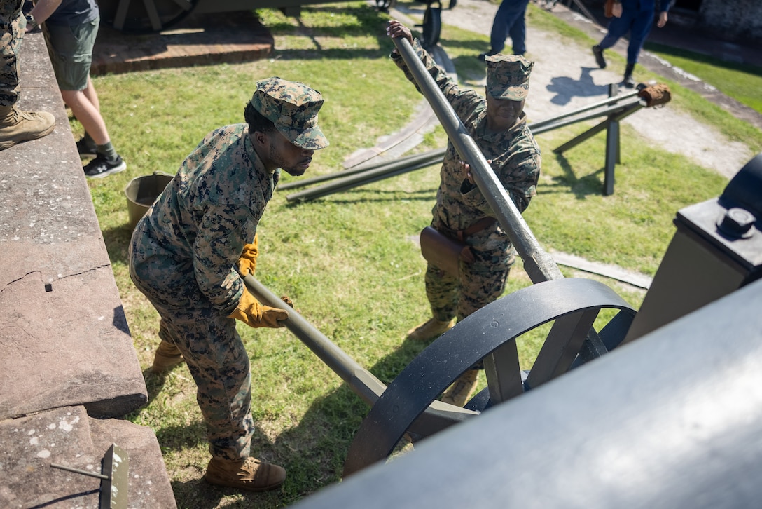 U.S. Navy Hospitalman Apprentice Jakobe Moore, left, a native of Alabama, and Hospitalman Tricel Walker, a native of New York, both hospital corpsmen with 1st Battalion, 10th Marine Regiment, 2nd Marine Division, push a Model 1841 Navy 32-pounder cannon out of battery during an evening gun ceremony at Fort Macon State Park, North Carolina, Aug. 27, 2025. Fort Macon fires Model 1841 Navy 32-pounder cannons weekly during the summer to honor the tradition of signaling the end of the military day by firing a solution charge. (U.S. Marine Corps photo by Lance Cpl. Brian Bolin Jr.)