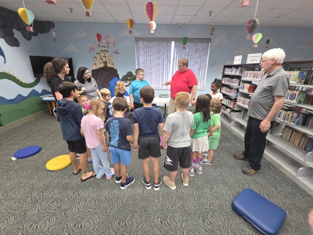 Members of the Strategic Weapons Facility Atlantic (SWFLANT) STEM Team show children at the Camden County Library that if they complete a circuit by joining hands, they can illuminate an energy stick during "Storybook STEM".