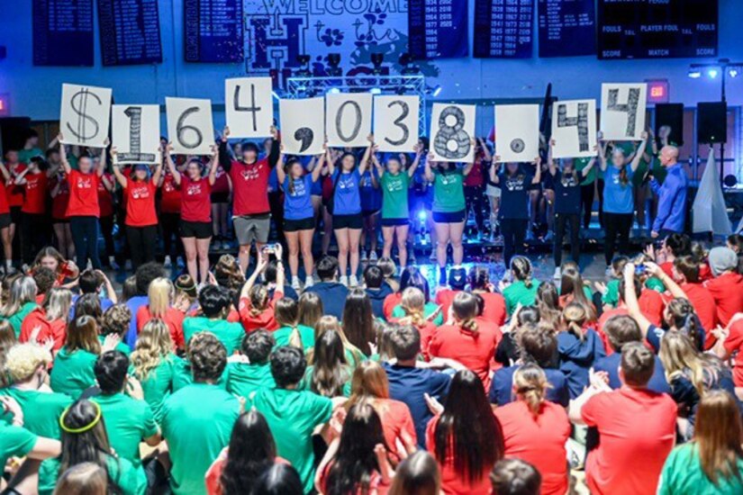 Students participating in the Creating Hope And Making Progress program hold up signs showing how much money they earned during a CHAMP event on Feb. 28, 2025, at Huntingdon High School.