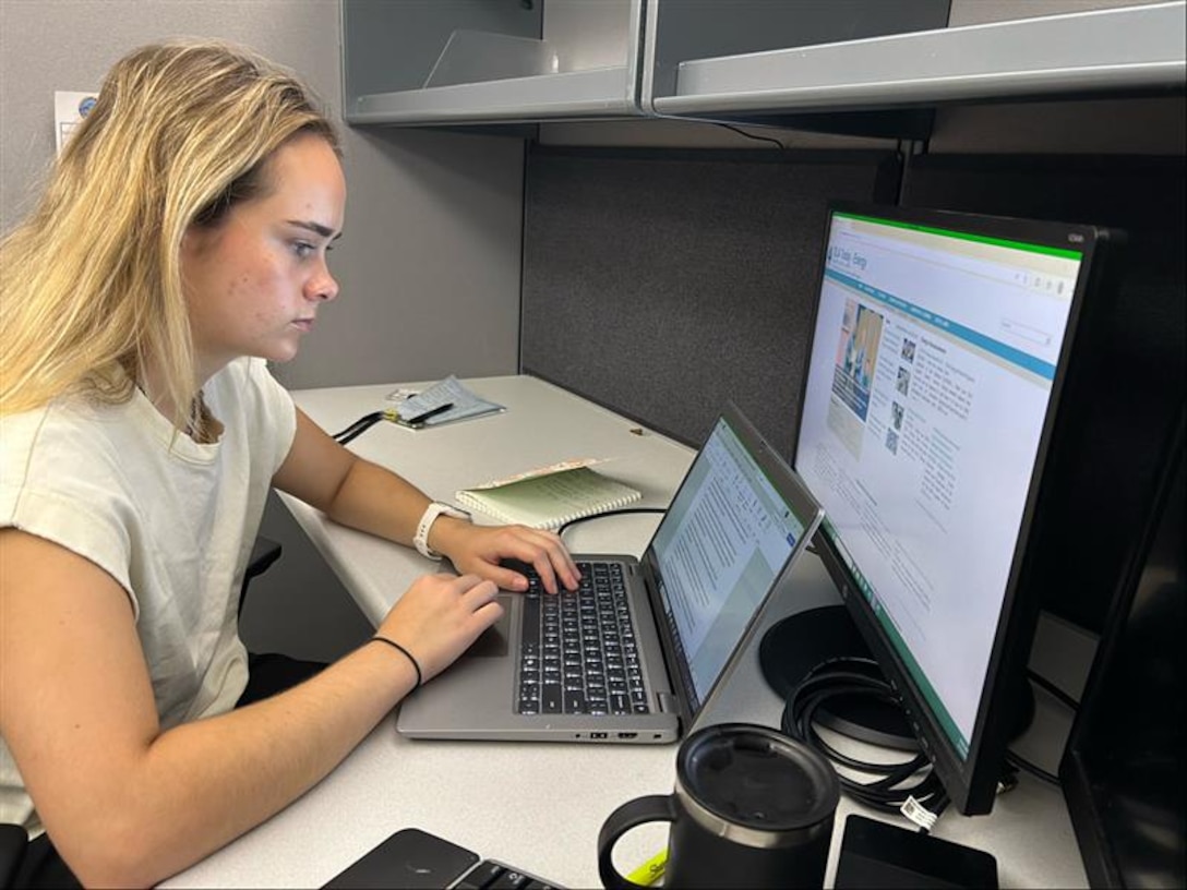 Woman sitting at a desk working on a laptop.