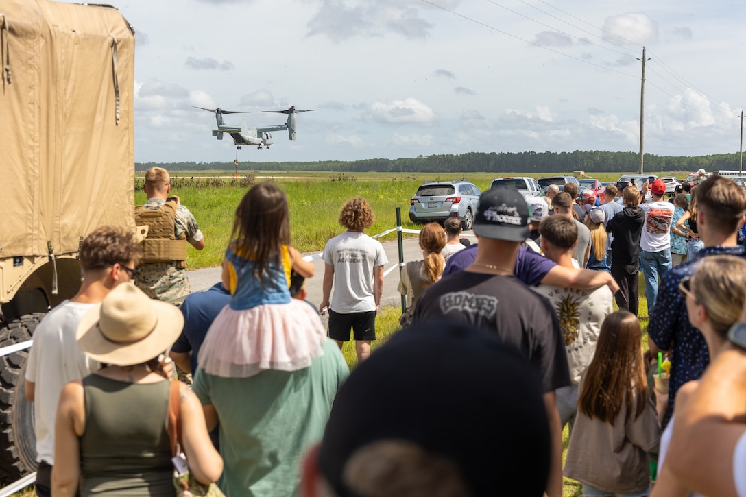 U.S. service members and their families watch Marines conduct fast-rope operations out of an MV-22 Osprey tiltrotor aircraft during a family day event at Camp Davis, Marine Corps Base Camp Lejeune, North Carolina, Aug. 23, 2025. The 26th Marine Expeditionary Unit hosted a family day for the Special Purpose Marine Air-Ground Task Force – Alert Contingency MAGTF (SPMAGTF-ACM) to give Marines and Sailors a chance to show their family members a glimpse of their day-to-day duties while also offering hands-on demonstrations of Marine Corps equipment and weapons. (U.S. Marine Corps photo by Lance Cpl. Jack Labrador)