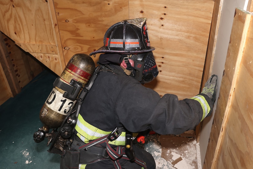 A Letterkenny Army Depot firefighter, wearing a mask that makes him completely blind, navigates his way to a breakthrough wall during firefighter training at the LEAD multi-purpose training facility on May 29.