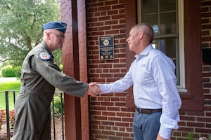 U.S. Air Force Lt. Gen. Mike Koscheski, deputy commander of Air Combat Command, and retired Maj. Gen. John McMullen shake hands during the McMullen House dedication