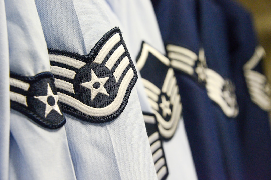 Air Force service uniform shirts and coats hang from an open closet