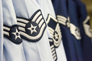 Air Force service uniform shirts and coats hang from an open closet