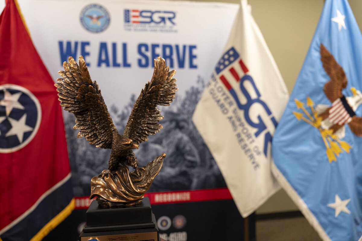A large trophy fashioned in the shape of a flying eagle rests in a room with flags in the background.
