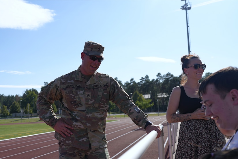 Staff Sgt. Stephen Burkham, an Army medic with the 7th Mission Support Command, talks with Kaiserslautern High School athletes and families during football practice in Kaiserslautern, Germany. Burkham, along with Lt. Col. Juanita Dubon, was recognized for providing lifesaving aid to a player last fall.
