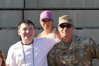 Kaiserslautern High School student Aiden, center, sits with his family and Staff Sgt. Stephen Burkham, right, and Lt. Col. Juanita Dubo, top, after returning to the football field months after a medical emergency during a game. Burkham and Dubon, both Army Reserve Soldiers, are credited with saving Aiden’s life through their volunteer medical support.