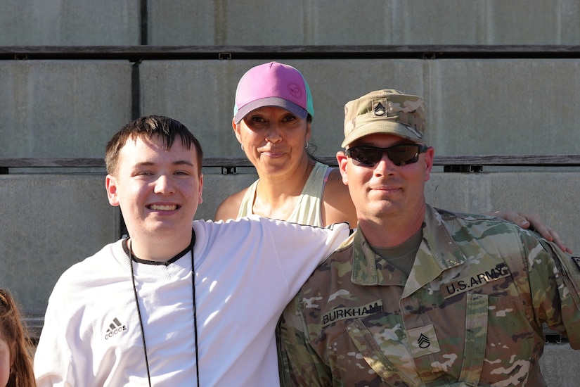 Kaiserslautern High School student Aiden, center, sits with his family and Staff Sgt. Stephen Burkham, right, and Lt. Col. Juanita Dubo, top, after returning to the football field months after a medical emergency during a game. Burkham and Dubon, both Army Reserve Soldiers, are credited with saving Aiden’s life through their volunteer medical support.