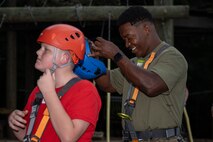 U.S. Marine Corps Staff Sgt. Mikelson Saintfleur, a motor transportation officer assigned to Special Purpose Marine Air-Ground Task Force 250 and a Young Marine from Middle Georgia Young Marines Program gear up to take part in the confidence course at Camp Southern Ground, Fayetteville, Georgia during Marine Week Atlanta, Aug. 30, 2025. Marines stationed across the globe commemorate the 250th anniversary of the Marine Corps, honoring a distinguished legacy of service, sacrifice, and unwavering fidelity to both the nation and the Corps. (U.S. Marine Corps photo by Sgt. Alexis French)