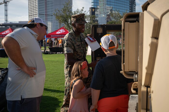 U.S. Marine Corps Lance Cpl. Shawn Harris a Motor Vehicle Operator assigned to Special Purpose Marine Air-Ground Task Force-250 show aspects of an up armored High Mobility Multipurpose Wheeled Vehicle (HUMMVEE), to Atlanta locals, at the static display as part of Marine Week Atlanta, Georgia during Marine Week Atlanta, Aug. 30, 2025. Marines stationed across the globe commemorate the 250th anniversary of the Marine Corps, honoring a distinguished legacy of service, sacrifice, and unwavering fidelity to both the nation and the Corps. (U.S. Marine Corps photo by Sgt. Alexis French)
