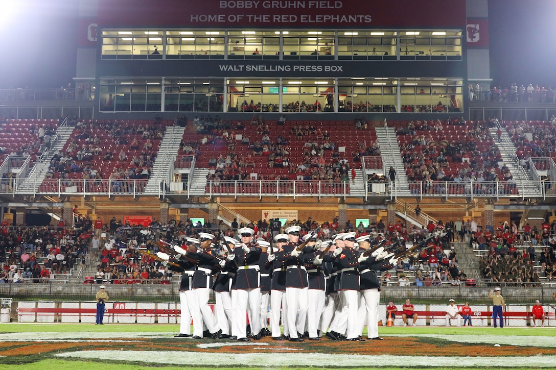 U.S. Marines with the United States Marine Corps Silent Drill Platoon execute their "bursting bomb" sequence during a half-time performance at a Gainesville High School football game during Marine Week Atlanta in Gainesville, Ga., Aug. 29, 2025. The year 2025 marks the 250th anniversary of the United States Marine Corps, a milestone that highlights the legacy, transformation and enduring spirit of the Corps since 1775. Throughout the year, Marines across the globe will commemorate this anniversary by honoring the service and sacrifice of those who served before them and by remaining faithful to the motto Semper Fidelis. (U.S. Marine Corps photo by Cpl. Christopher Prelle)